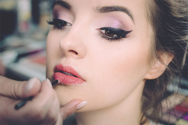 a woman is putting on makeup with a brush.