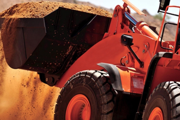 a large orange truck driving down a dirt road.