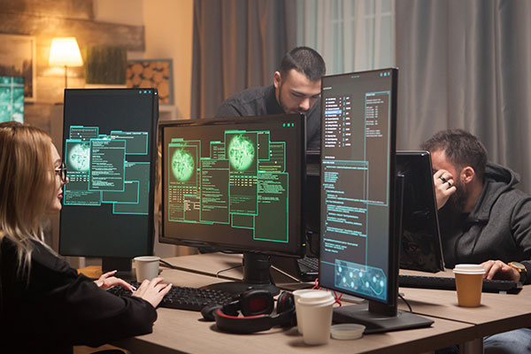 a group of people sitting at a table working on computers.