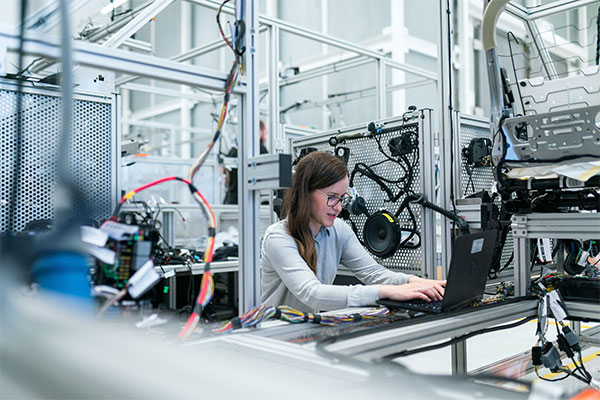 a woman working on a laptop in a factory.