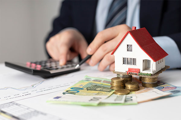 a man in a business suit with a calculator and a house model on.